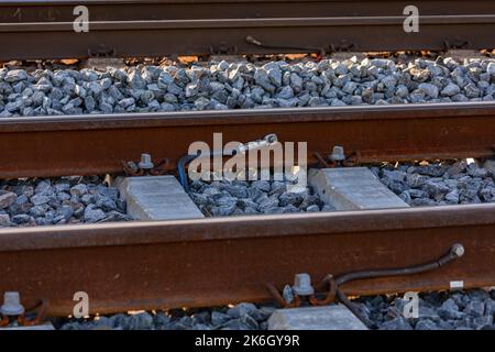 Cosses de câble sur un rail sur une voie ferrée dans un banc de ballast Banque D'Images