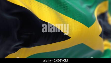 Vue rapprochée du drapeau national de la Jamaïque qui agite dans le vent. La Jamaïque est un pays insulaire situé dans la mer des Caraïbes. Arrière-plan texturé en tissu. Banque D'Images