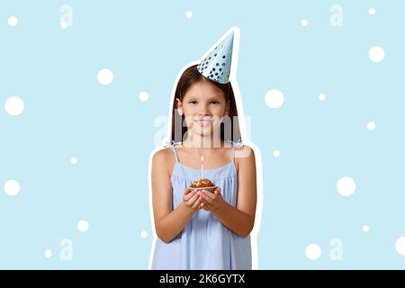 bonne petite fille d'anniversaire avec un cône de fête tenant le cupcake Banque D'Images