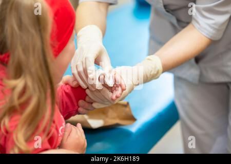 Les mains du médecin bandent le doigt douloureux avec un bandage de l'enfant.Blessure et blessure au doigt chez les enfants Banque D'Images