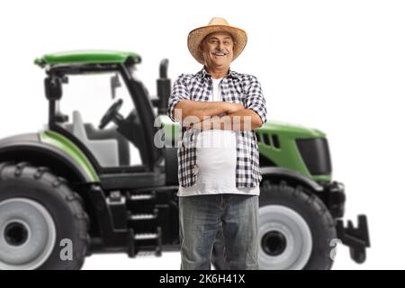Agriculteur mûr debout devant un tracteur vert isolé sur fond blanc Banque D'Images