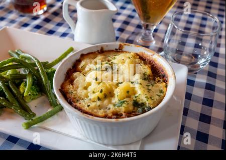 Tarte aux lentilles et aux champignons assaisonnée cuite lentement dans du vin rouge, recouverte de purée de cheddar et servie avec des légumes de saison de gros plan Banque D'Images