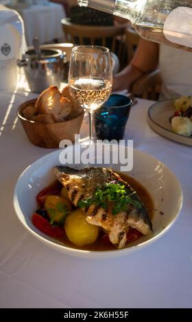 Cuisine provençale, filet grillé de poisson blanc au seabass servi avec des pommes de terre, des tomates et du jus de poisson Bouillabaisse dans le restaurant français Banque D'Images
