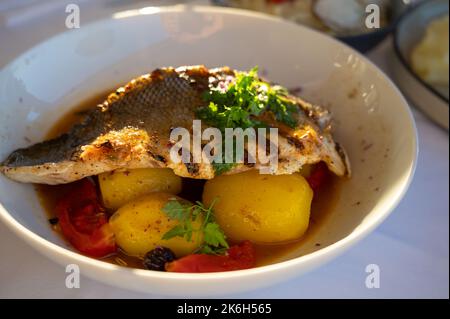 Cuisine provençale, filet grillé de poisson blanc au seabass servi avec des pommes de terre, des tomates et du jus de poisson Bouillabaisse dans le restaurant français Banque D'Images