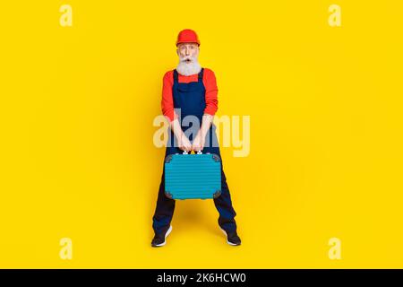 Photo pleine longueur d'un ouvrier expérimenté, kit de boîte à outils de maintien impressionné isolé sur fond de couleur brillante Banque D'Images