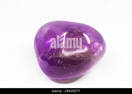 Macro en pierre d'Amétrine tumblée réelle isolée sur une surface blanche. Cristal violet avec un peu de coloration jaune à l'extrémité Banque D'Images