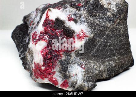 Macro de morceau de pierre Cinnabar rouge véritable brut isolée sur la surface noire Banque D'Images