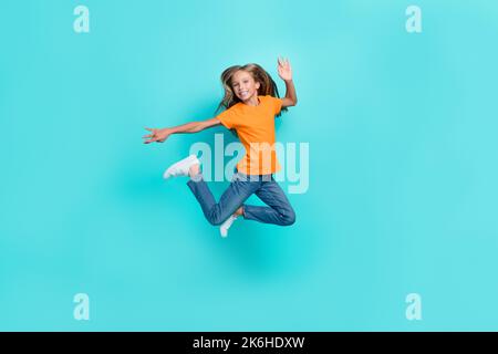 Photo sur toute la longueur du corps de l'excitée fou joli écolier fille saut air trampoline insouciante main mouvement acitivité isolé sur la couleur de l'aigue-marine Banque D'Images