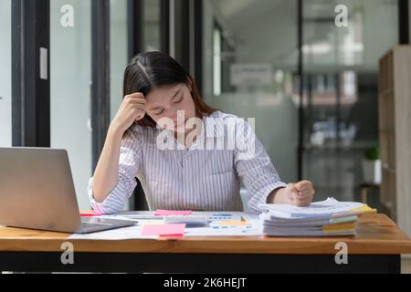 Femme asiatique travaillant dur avec le stress sérieux et les maux de tête tout en ayant un problème au travail en officee, femme travaillant dur concept. Banque D'Images