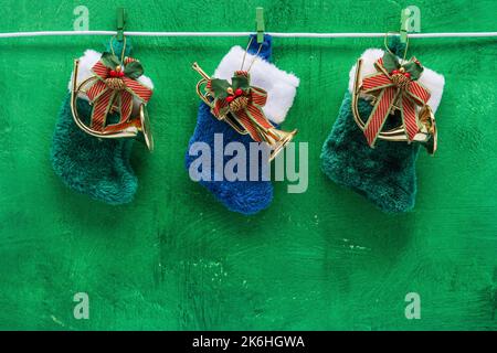 Thème de Noël avec bas en fourrure accrochés sur une corde à linge avec ornements en corne de laiton et fond vert brillant texturé Banque D'Images