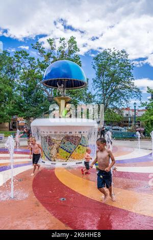 Colorado Springs, CO - 3 juillet 2022 : les enfants jouent dans les fontaines entourant la fontaine de l'oncle Wilbur lorsqu'elle s'active pour révéler un pla sousaphone Banque D'Images