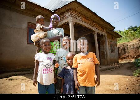 Une femme âgée se tient avec ses cinq petits-enfants devant leur maison en briques dans le district de Kasese, en Ouganda, en Afrique de l’est. Banque D'Images