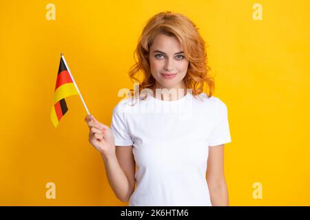 Portrait d'une étudiante positive portant le drapeau allemand. Isolé sur fond jaune. Bonne fille tenant le drapeau de l'Allemagne, l'immigration et les voyages Banque D'Images