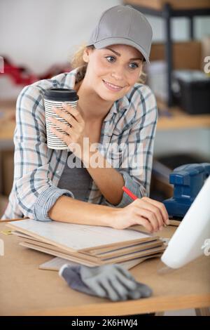 une femme mécanicien portant un capuchon est assise sur un bureau pour tenir le café Banque D'Images