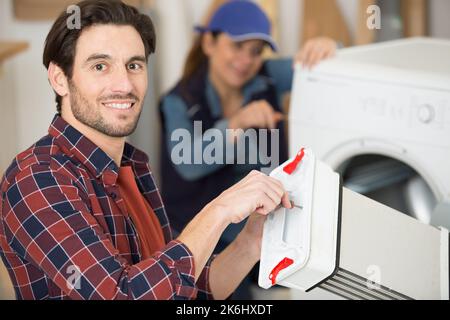 agent de service tenant la partie condeser d'un sèche-linge Banque D'Images