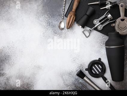 Divers ustensiles de cocktail. Puzzle en cuivre, paille et cuillère avec shaker noir, garde-boue et passoire sur fond clair avec bac en caoutchouc noir. Vue du dessus. Banque D'Images