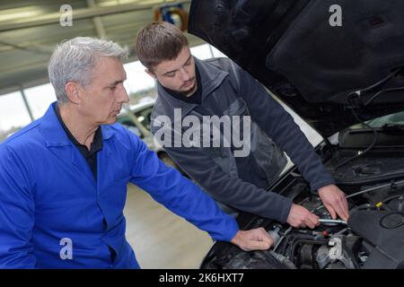 Avec moniteur étudiant la réparation d'une voiture pendant l'apprentissage Banque D'Images