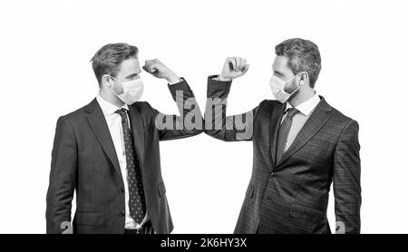 les hommes d'affaires en masque se cognent les coudes au lieu de serrer les mains pour éviter le contact, salutation d'affaires. Banque D'Images
