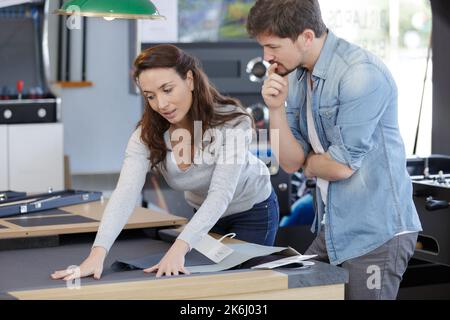 le directeur du magasin présente des échantillons de tissus Banque D'Images