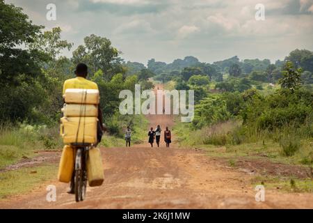 Trafic piétonnier et cycliste sur une route rurale dans le district d'Amuria, en Ouganda, en Afrique de l'est. Banque D'Images