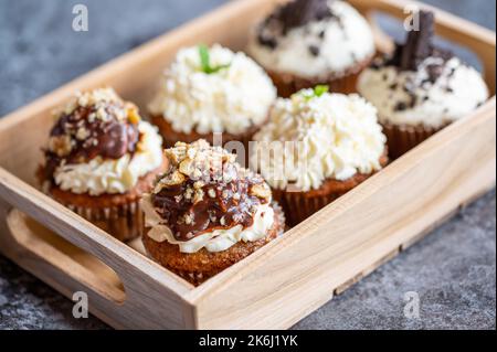 Petits gâteaux et muffins placés dans une boîte en bois. Chocolat et crème aux noix. Des bonbons frais faits maison. Banque D'Images