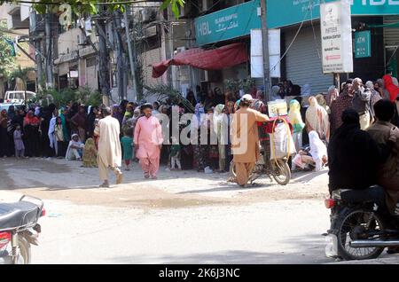 Un grand nombre de femmes pauvres bénéficiaires du Programme de soutien du revenu Benazir Bhutto (BISP) se réunissent à leur tour pour obtenir de l'argent dans une banque située sur le Gulistan-e-Jauhar à Karachi vendredi, 14 octobre 2022. Banque D'Images