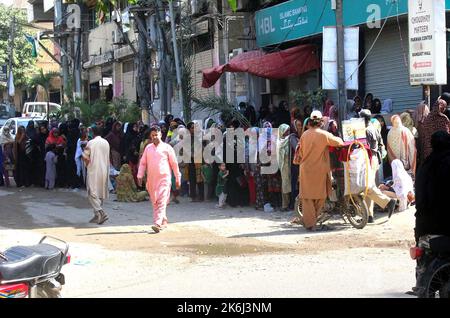 Un grand nombre de femmes pauvres bénéficiaires du Programme de soutien du revenu Benazir Bhutto (BISP) se réunissent à leur tour pour obtenir de l'argent dans une banque située sur le Gulistan-e-Jauhar à Karachi vendredi, 14 octobre 2022. Banque D'Images