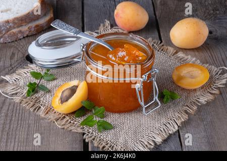 Confiture d'abricots dans un pot en verre sur une ancienne table en bois Banque D'Images