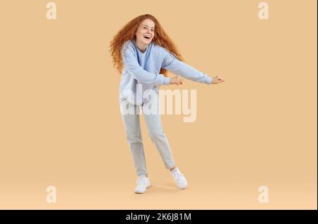 Portrait de drôle gai jeune femme en tenue décontractée dansant sur fond beige studio Banque D'Images