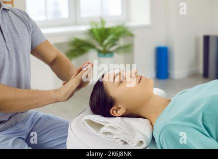 Jeune femme se détendant et de restaurer l'énergie pendant la séance de thérapie avec Reiki guérisseur Banque D'Images