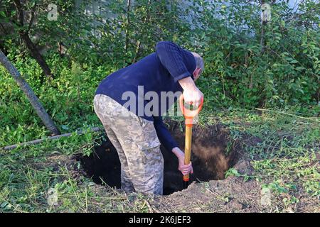 L'homme creuse une fosse profonde. L'homme se repose après le travail. Creuser une fosse à la pelle. Banque D'Images