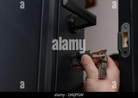 Le maître installe le noyau de la serrure de porte, le travail d'assemblage avec la porte, le noyau avec les clés. Banque D'Images