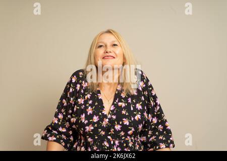 Gros plan portrait d'une jolie femme souriante avec haussement d'épaules demandant quel est le problème qui se soucie de quoi ou Je ne sais pas. Isolé sur fond beige. Négatif Banque D'Images