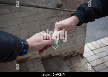 La main d'un drogué avec de l'argent, achète de la cocaïne ou de l'héroïne à un marchand. Concept de vente de médicaments. Banque D'Images