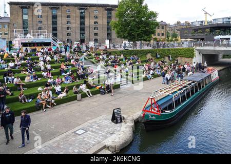 Personnes assises sur les marches de Granary Square à King's Cross, Londres Angleterre Royaume-Uni Banque D'Images