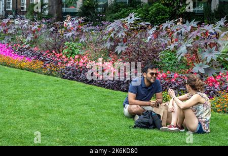 Un couple assis sur le Grass dans le Victorian Embankment Gardens Londres Royaume-Uni Banque D'Images