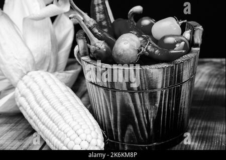 Épis de maïs avec piments et tomates légumes frais nourriture naturelle dans seau en bois, bio Banque D'Images