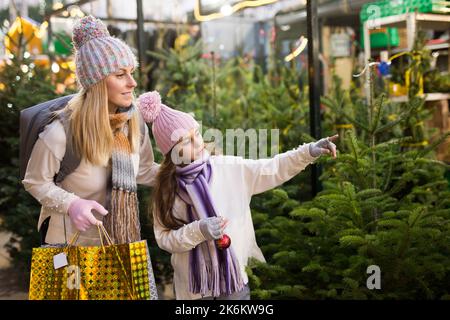 Préteen fille avec la mère sélectionnant arbre de Noël sur la foire extérieure Banque D'Images