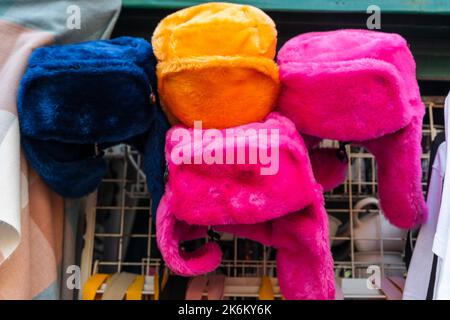 chapeaux en fourrure de couleur vive avec rabats sur le comptoir du vendeur de rue Banque D'Images