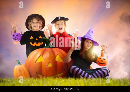 Petit garçon en costume de sorcière assis à la lanterne géante de citrouille le soir d'Halloween. Enfants trick or Treat. Enfants Amuse-toi bien. Célébration effrayante et effrayante. Banque D'Images