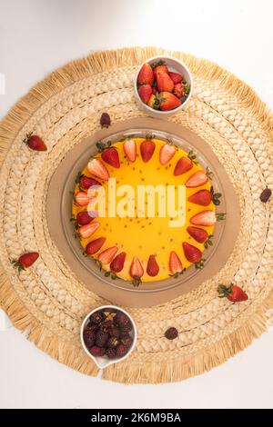 cheesecake aux fruits de la passion décoré de fraises et de mûres fraîches sur une table prête à manger, dessert sucré en studio, décoration d'assiette Banque D'Images