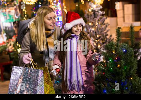 Préteen fille avec la mère sélectionnant arbre de Noël sur la foire extérieure Banque D'Images