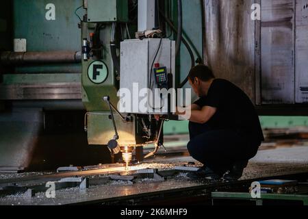 Le travailleur fait fonctionner la machine de forage dans l'atelier d'usine Banque D'Images