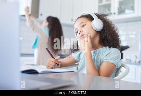 Parlez librement, vous pourriez changer le monde. une petite fille regardant bien réfléchie faisant ses devoirs à la table de cuisine. Banque D'Images