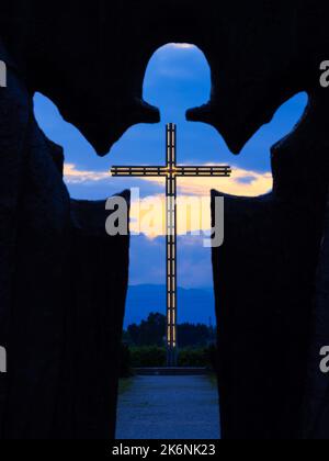 Brezje, Slovénie - 28 juillet 2022: Une vue de l'heure bleue à travers la silhouette de l'enfant Jésus sur une grande croix illuminée Banque D'Images