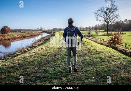 Randonneur mâle avec sac à dos marchant seul sur le chemin de l'herbe en automne. Banque D'Images