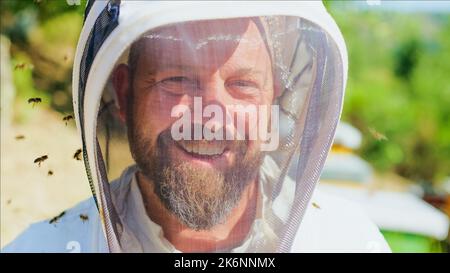 Les abeilles volent autour de la face protégée d'un apiculteur Banque D'Images