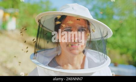 Les abeilles volent autour de la face d'un apiculteur Banque D'Images