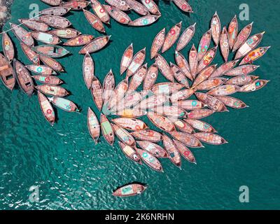 Des centaines de bateaux en bois détournent leurs amarres dans des motifs qui ressemblent aux pétales de fleur pour un trajet matinal très chargé sur le fleuve Buriganga. Banque D'Images