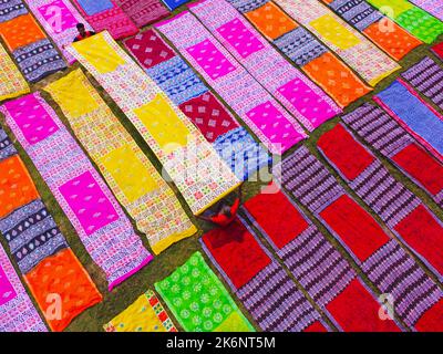 Les employés sèchent des chiffons colorés en rangées nettes sur un champ. Les tissus sont localement appelés 'Saree' - un vêtement traditionnel pour les femmes. Banque D'Images